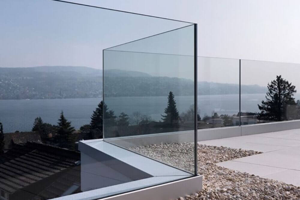 Ringhiera in vetro su una terrazza con vista su un lago e montagne.