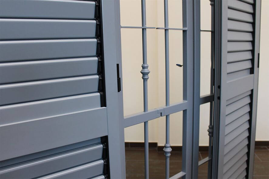 Persiane esterne grigie, con cancellata in ferro battuto dello stesso colore, aperte.