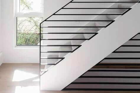 Moderna scala bianca e nera con ringhiera in metallo, vicino a una finestra.