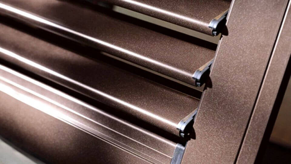Persiane metalliche marroni con lamelle luminose e texture granulosa.