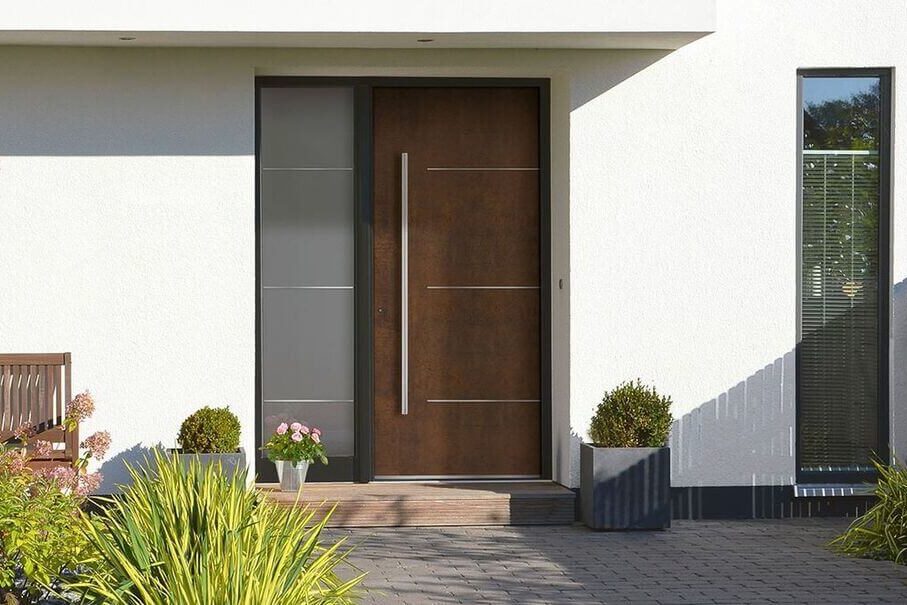 Ingresso moderno con porta marrone scuro, pannelli laterali in vetro satinato e piante decorative.