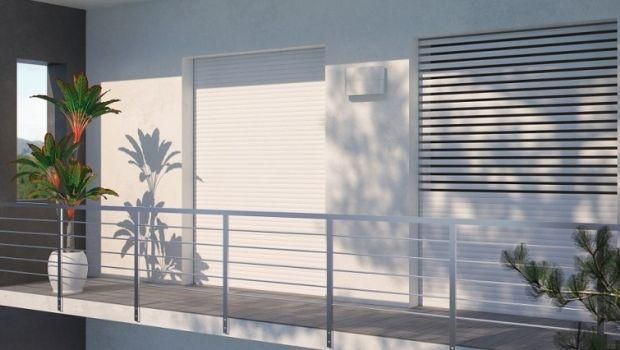 Balcone moderno con ringhiere metalliche, piante in vaso e persiane chiuse.