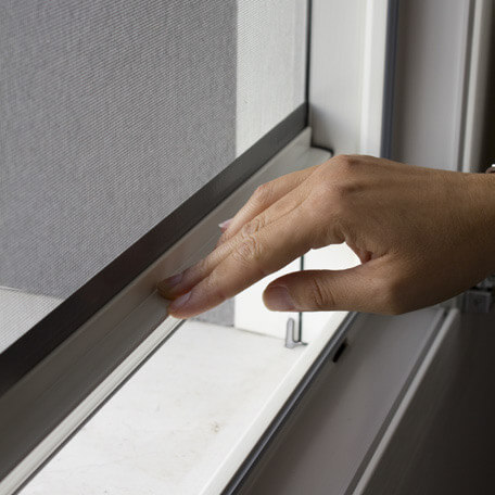 Primo piano di una mano che chiude una zanzariera.